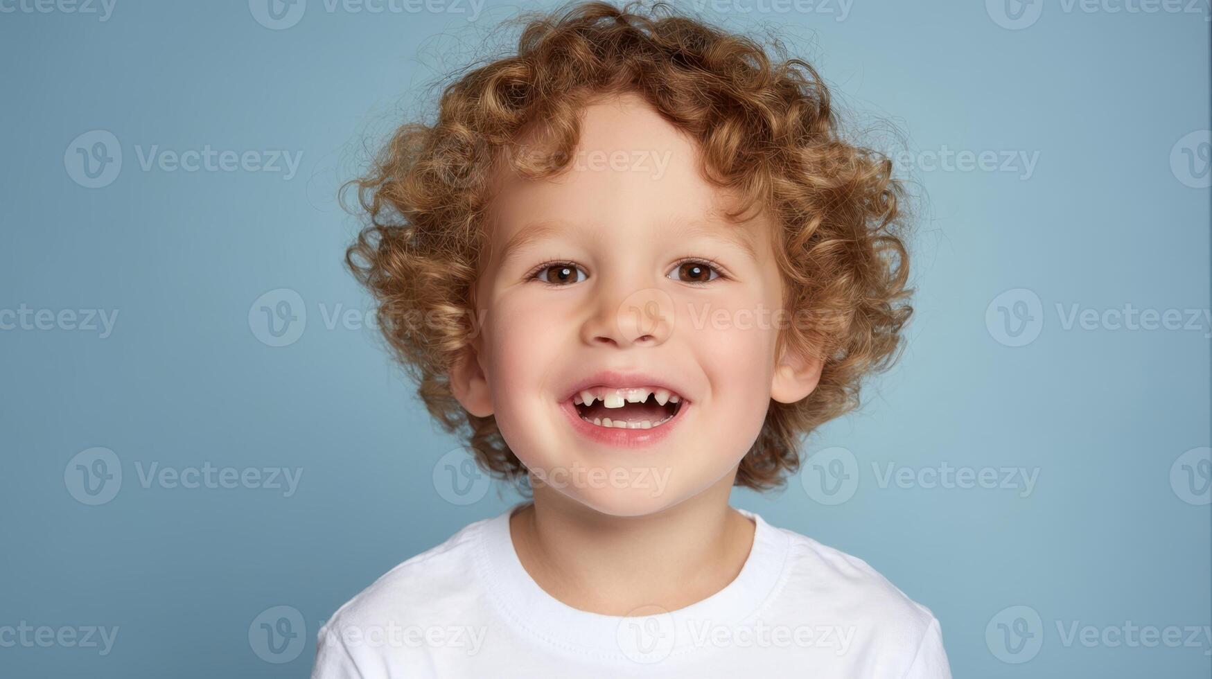 The joyful child with curly hair smiling at the camera against a blue background. photo