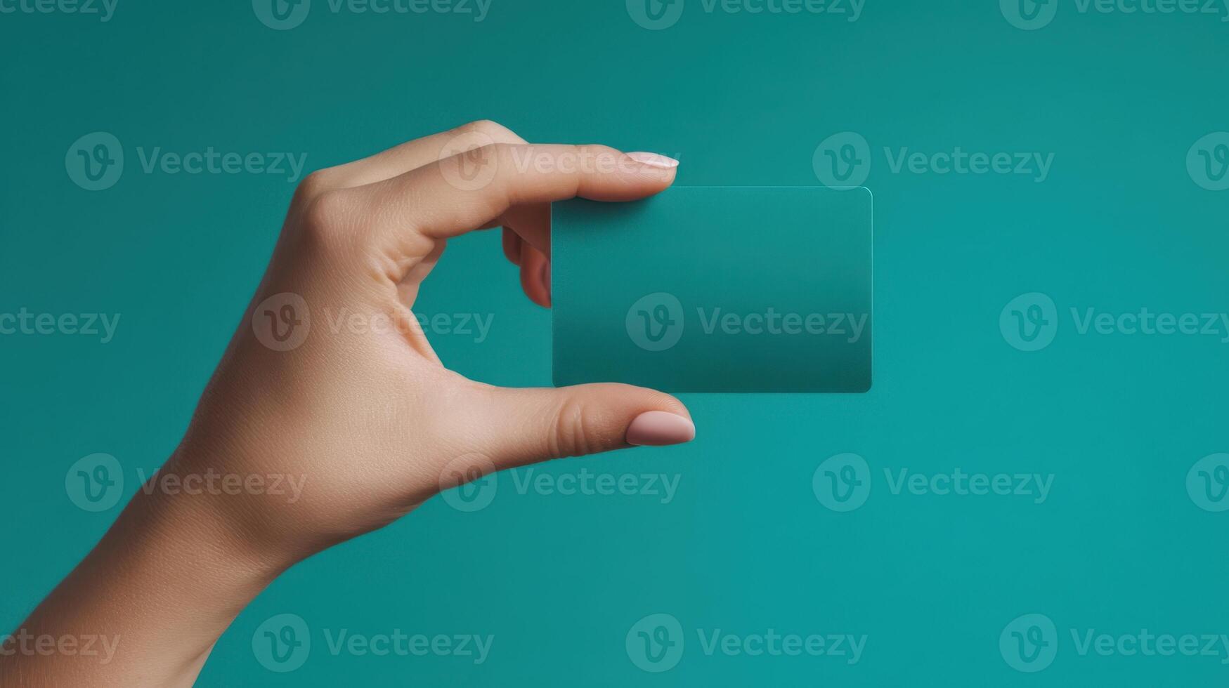 The hand holding a blank card against a teal background photo