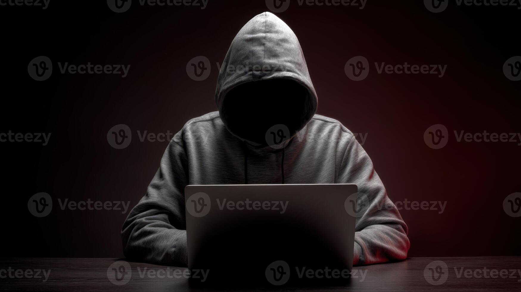 The hooded figure working secretly on a laptop in a dark environment. photo