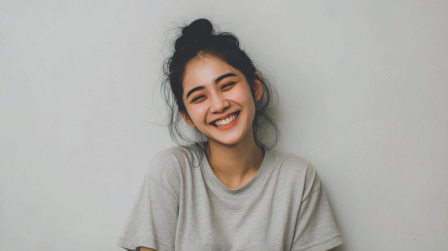 A woman smiling while sitting on a white wall photo