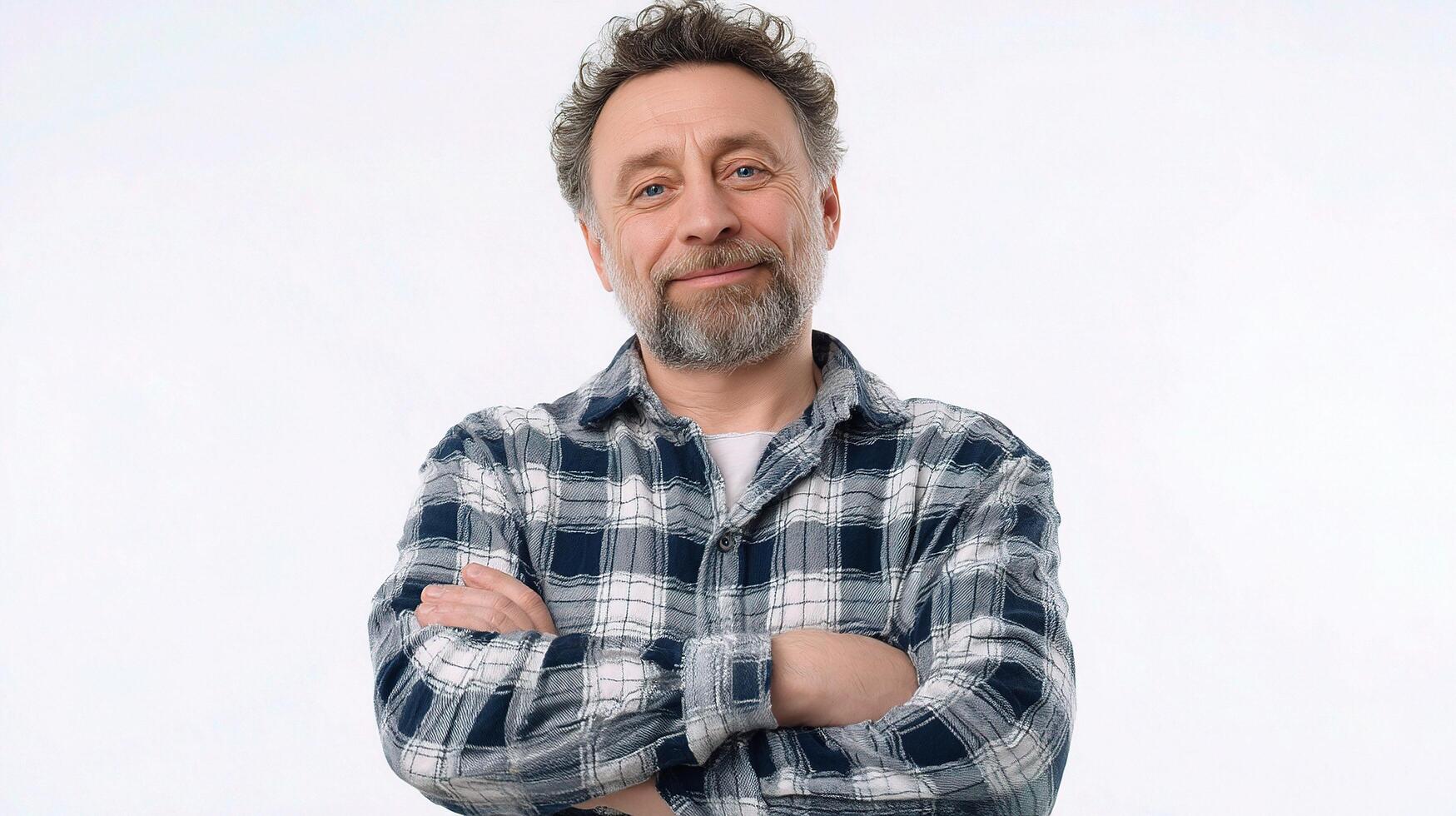 A man with a beard and plaid shirt standing with his arms crossed photo
