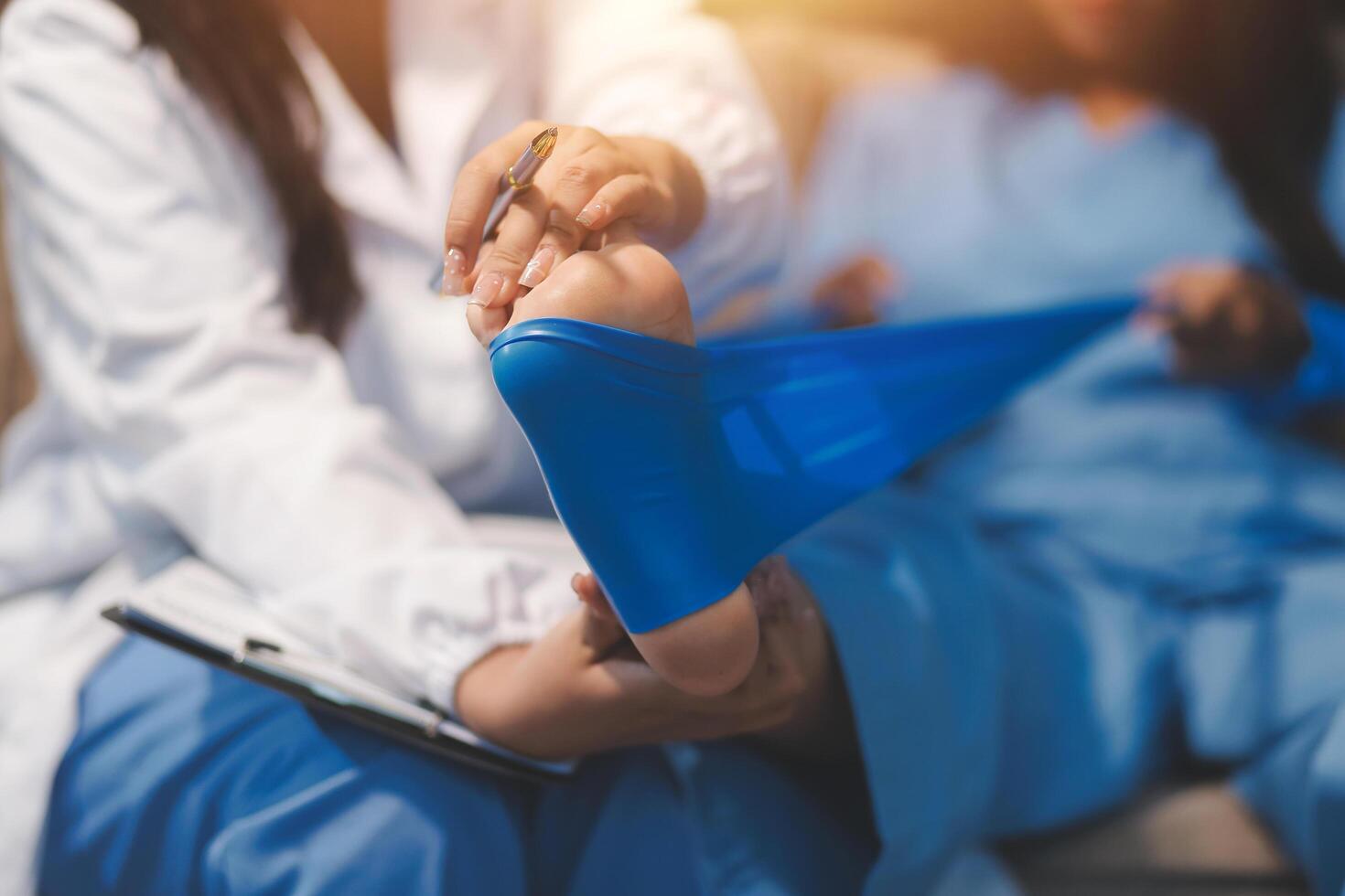 A doctor is holding a blue bandage to a woman's foot photo