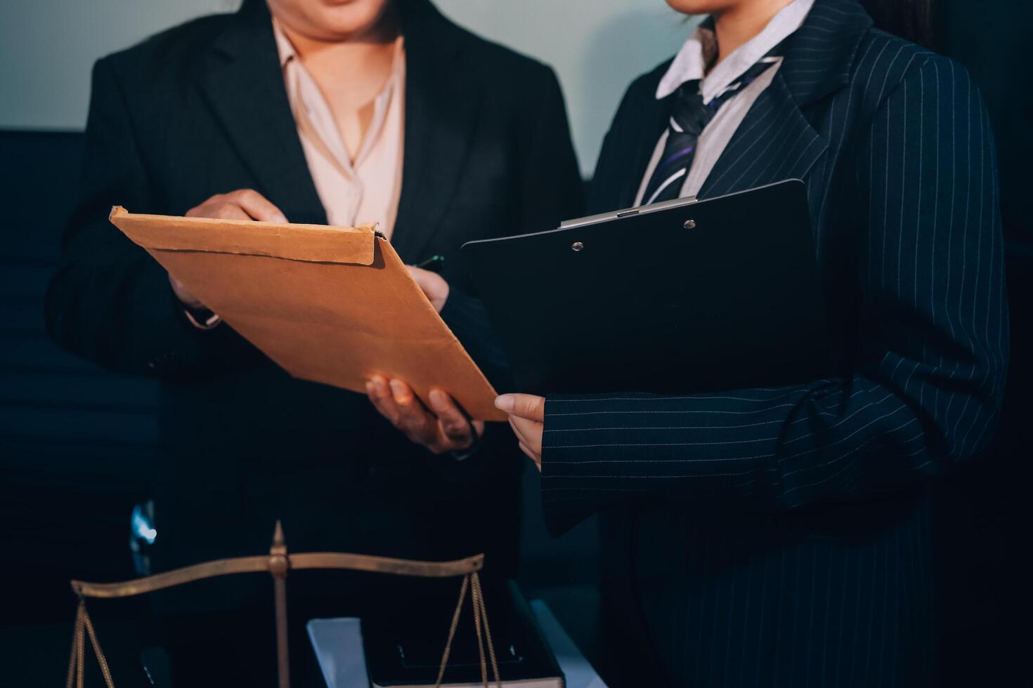 Two business people in suits holding a folder and a scale photo