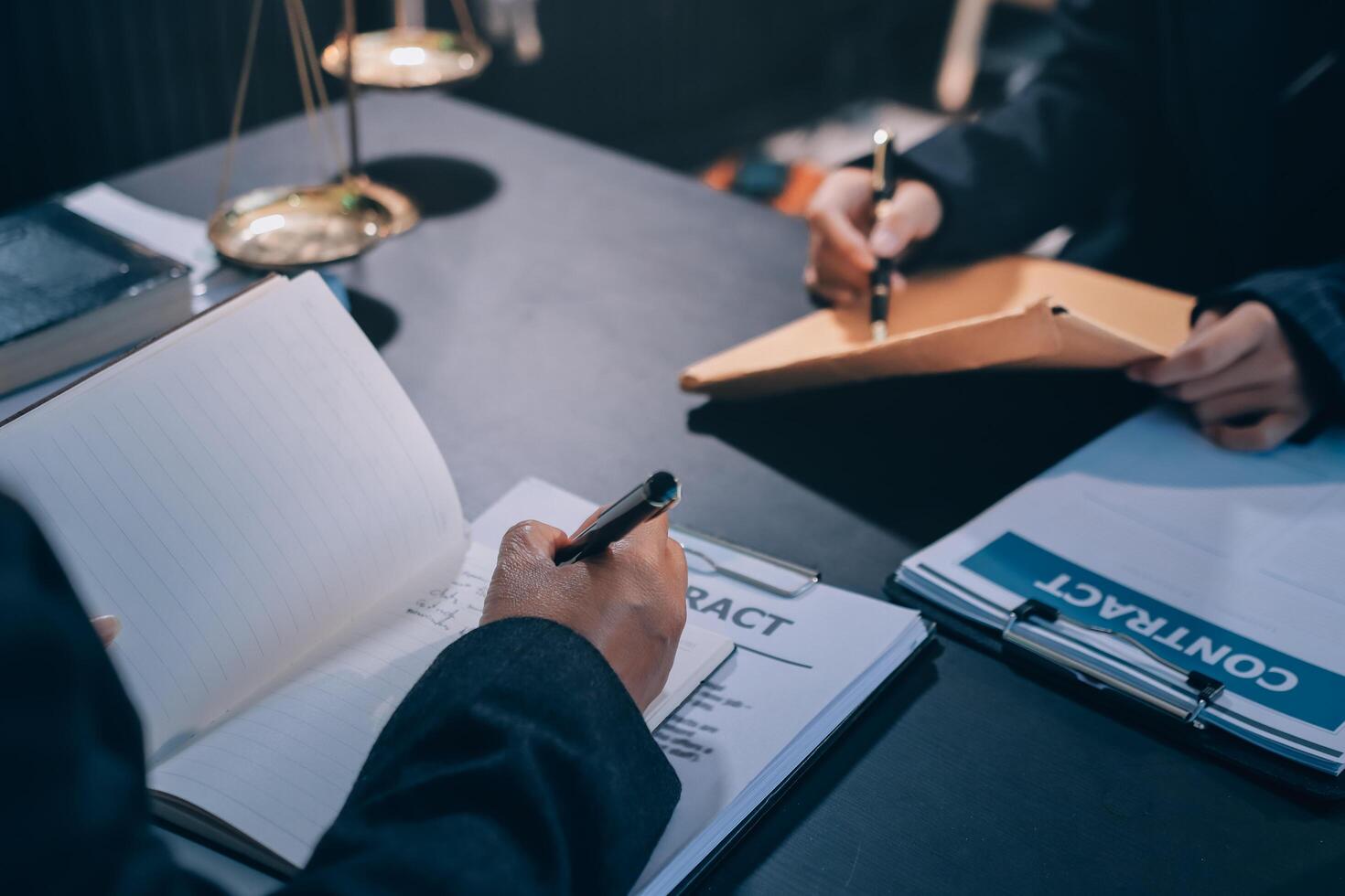 A lawyer is writing on a paper while a client is signing a contract photo