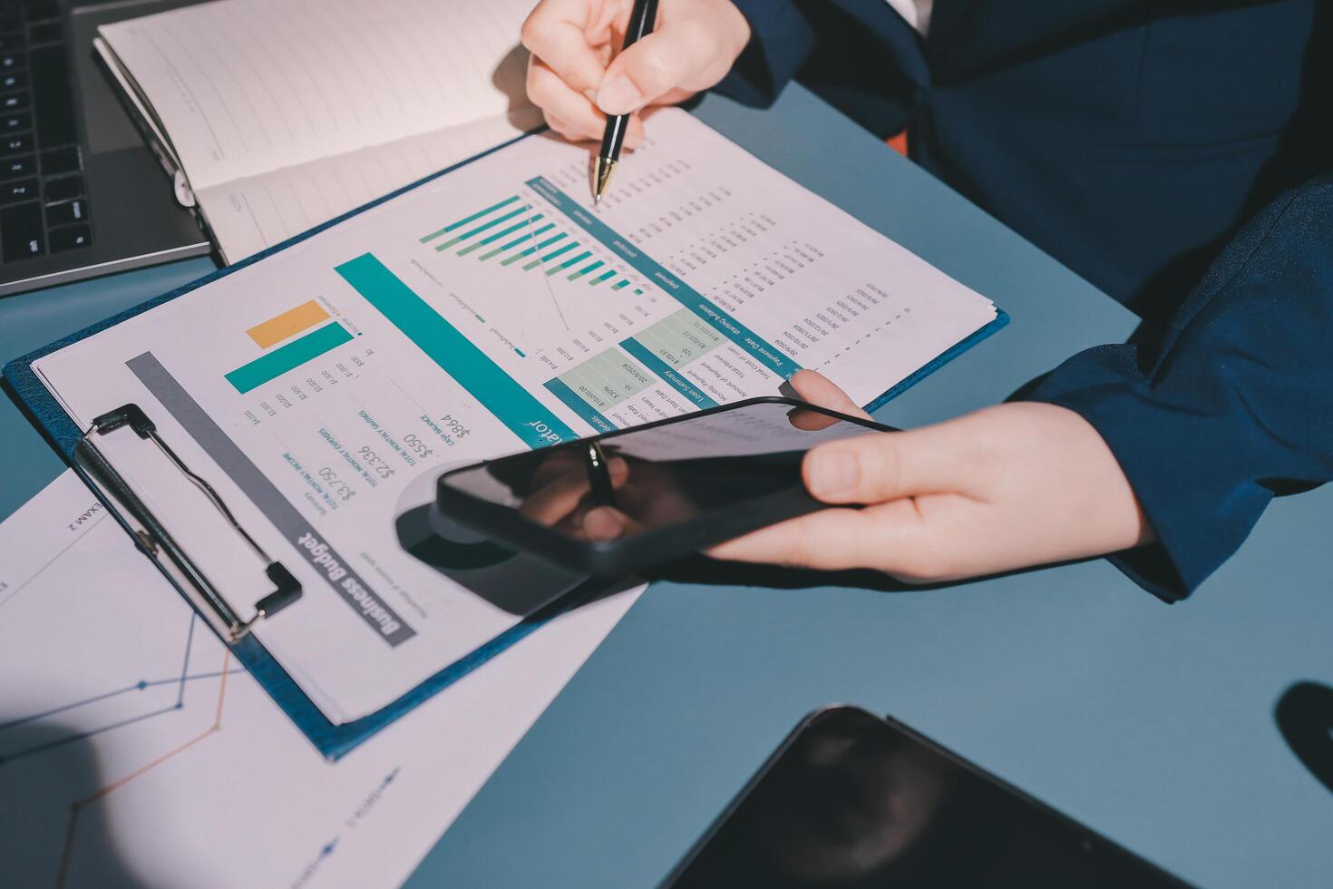 Businessman using a laptop and pen to write on a business document photo