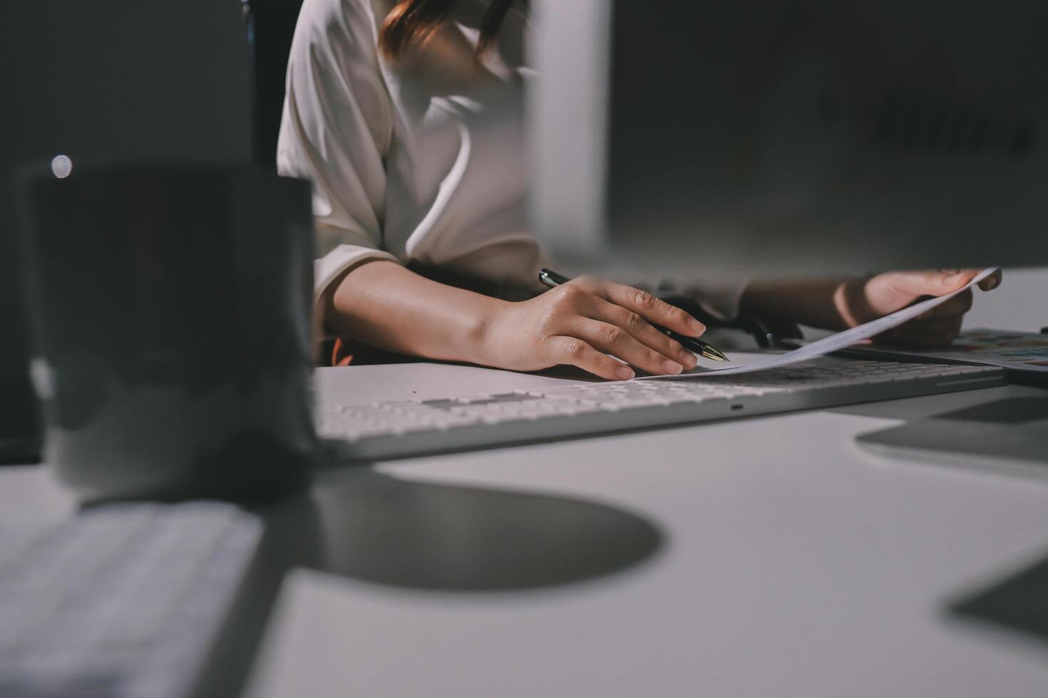 A person sitting at a desk with a computer and a keyboard photo