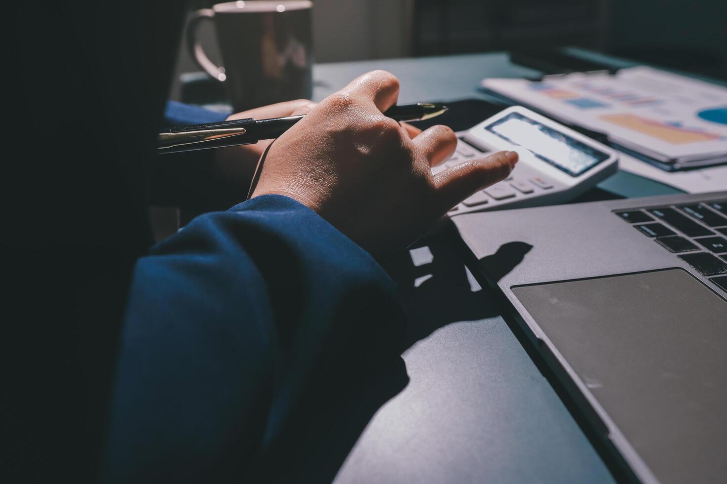 A person using a calculator and pen on a laptop photo