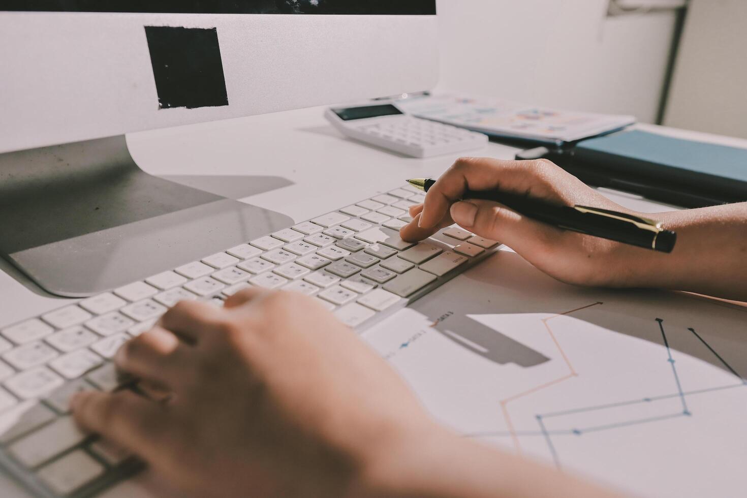 A person is typing on a keyboard and a pen photo
