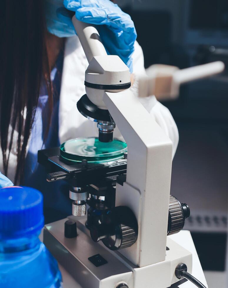 A woman in a lab coat is looking at a green object photo