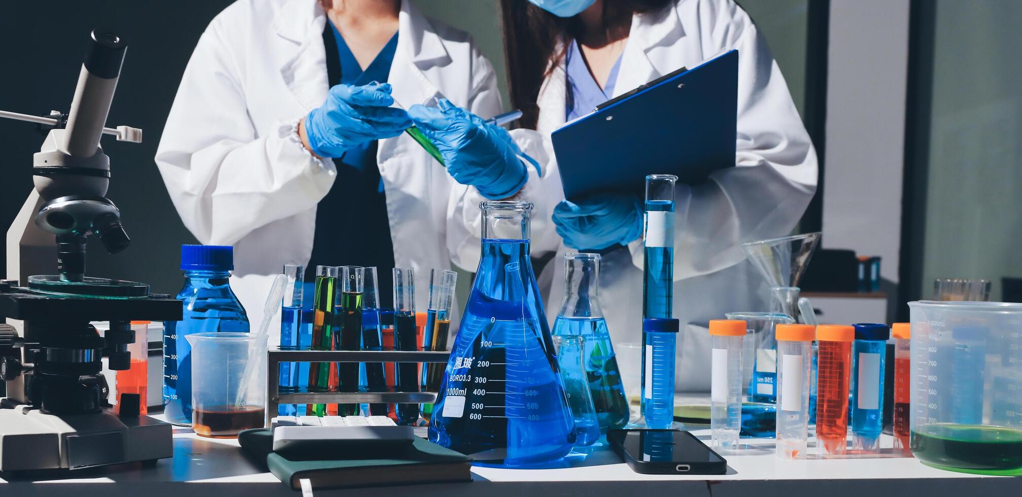 Two people in lab coats and gloves are looking at something photo