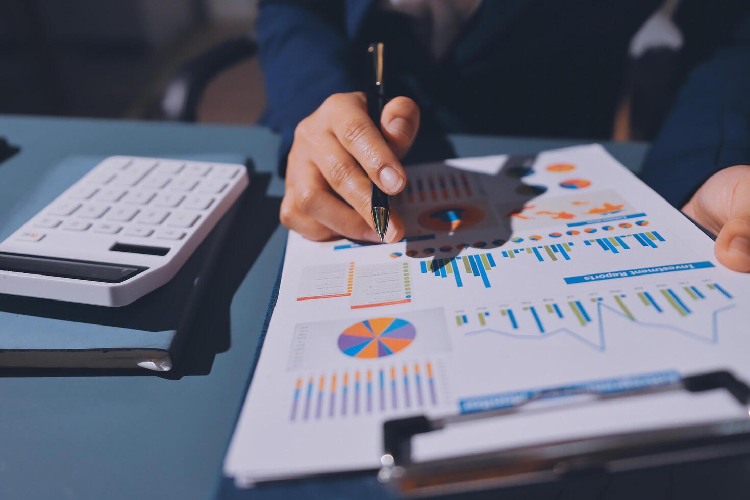 Businessman's hand writing on a paper with graphs and business data photo