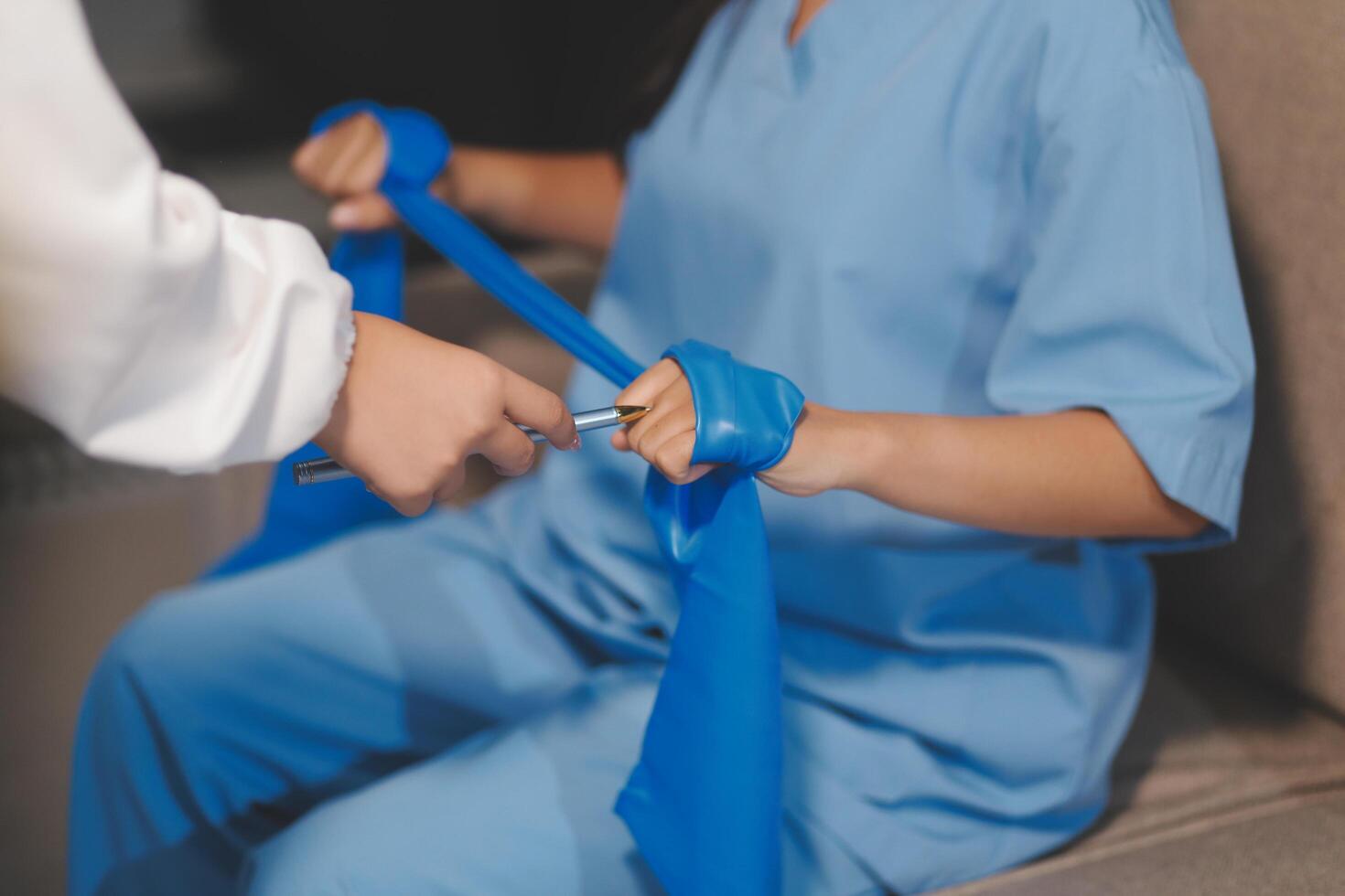 A woman in scrubs is tying a blue bandage around her arm photo