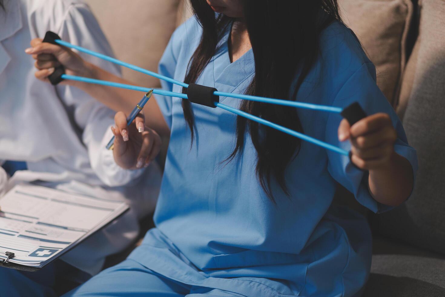 A woman in scrubs holding a clipboard while another woman sits on a couch photo