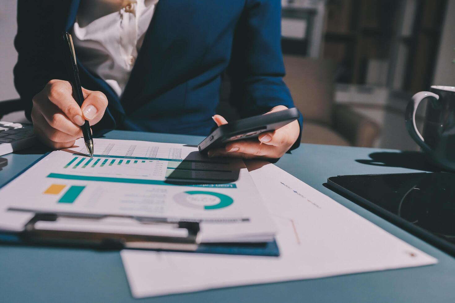 A woman in a business suit is using a calculator and pen to write on a piece of paper photo