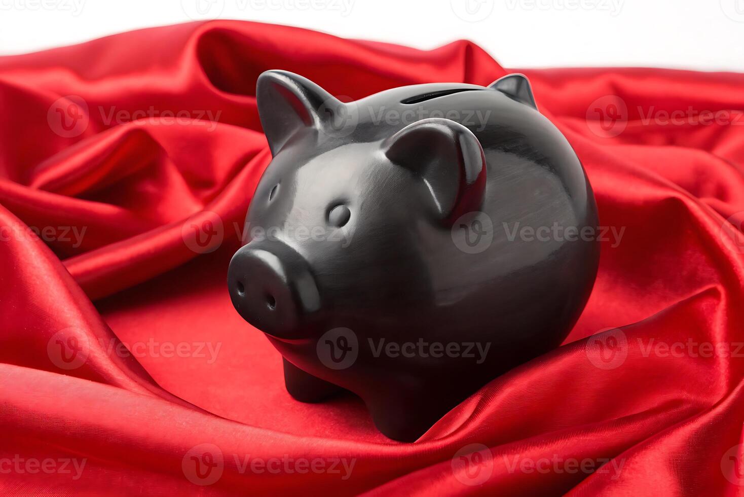 a black piggy bank sitting on a red satin cloth photo