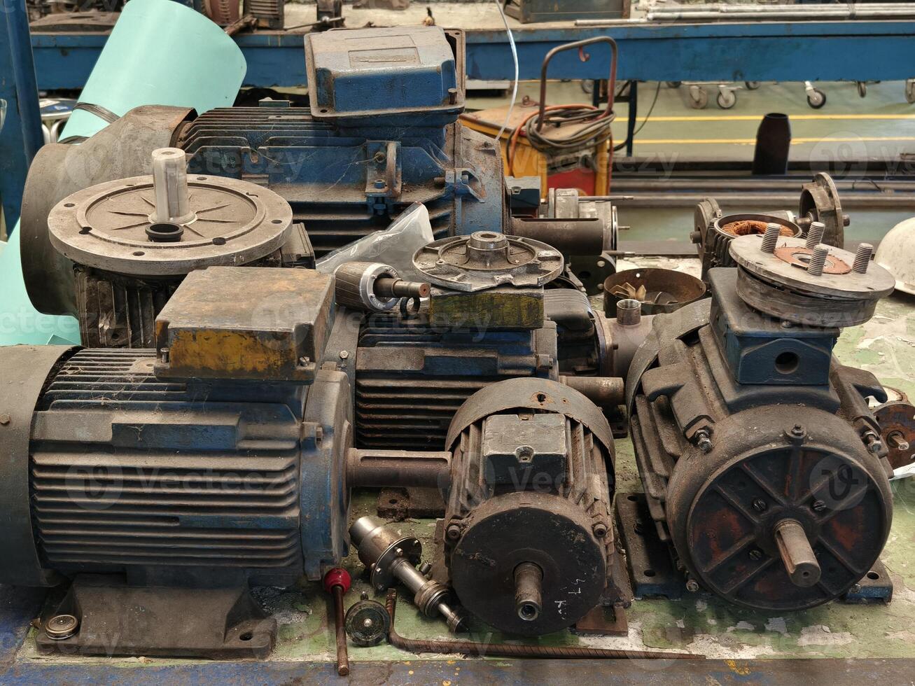 Stack of Old Disassembled Electric Motors on a Workbench in a Workshop photo