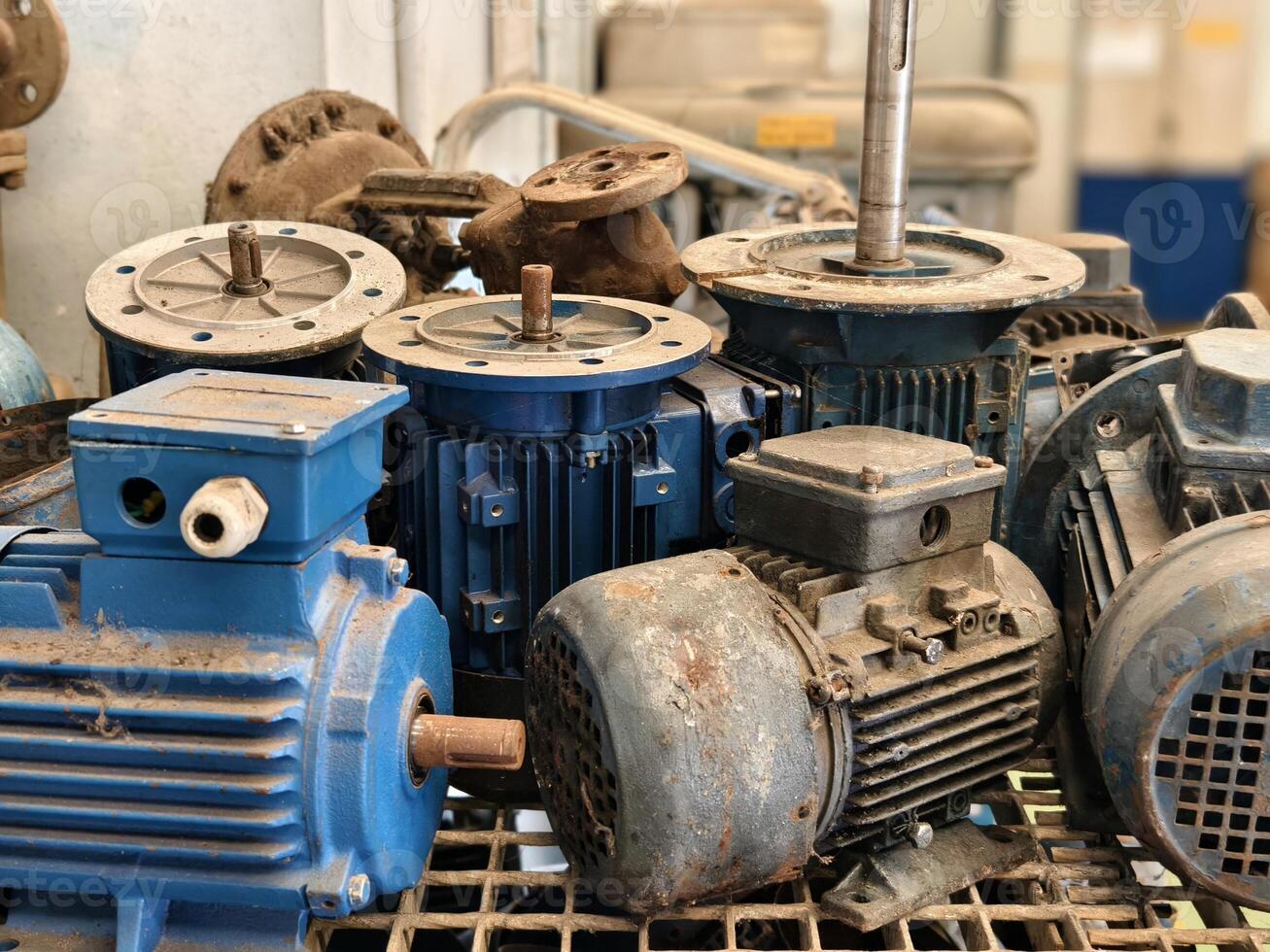 A used electric motor with visible rust and disassembled parts, placed in an industrial workspace photo