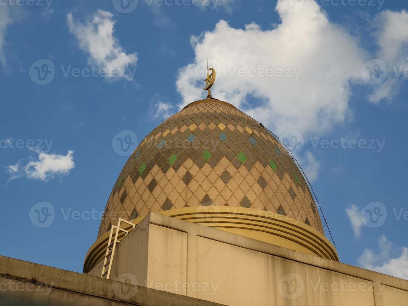 Ornate Mosque Dome with Crescent Moon Symbol Against Blue Sky and White Clouds photo