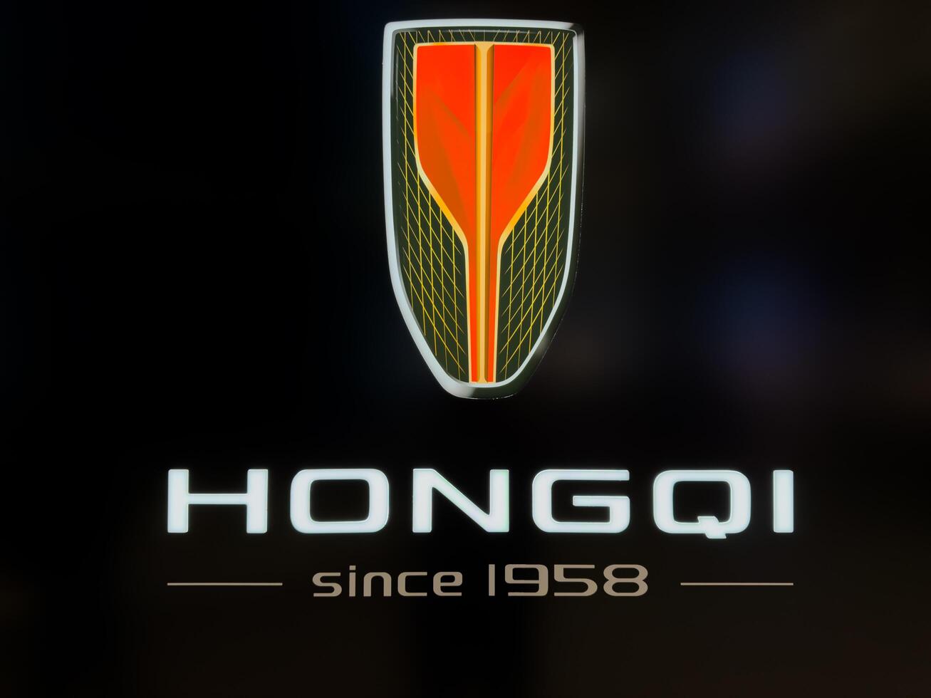 Moscow, Russia, April 25, 2025 Close up view of illuminated Hongqi logo with brand slogan since 1958 on dark background, showcasing the identity of the Chinese luxury car manufacturer photo