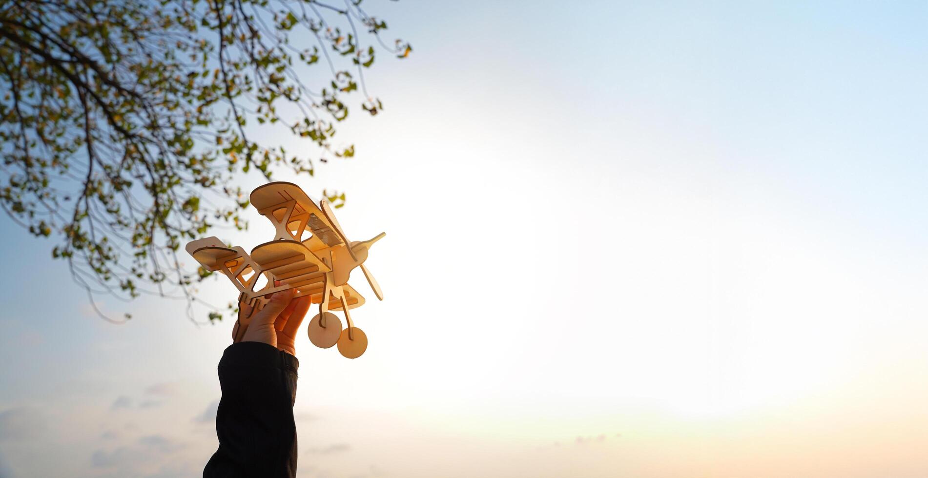 A person is holding a model airplane in the air. The sky is blue and the sun is shining brightly. photo