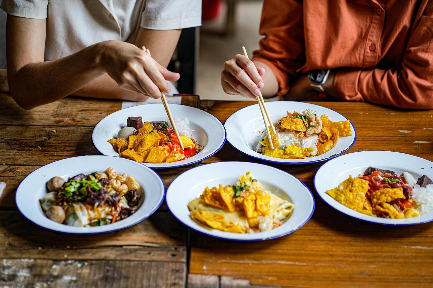 Young Asian couple traveler tourists eating Thai street food together in Laplae District market in Uttaradit Province, Thailand - people traveling enjoying food culture concept photo