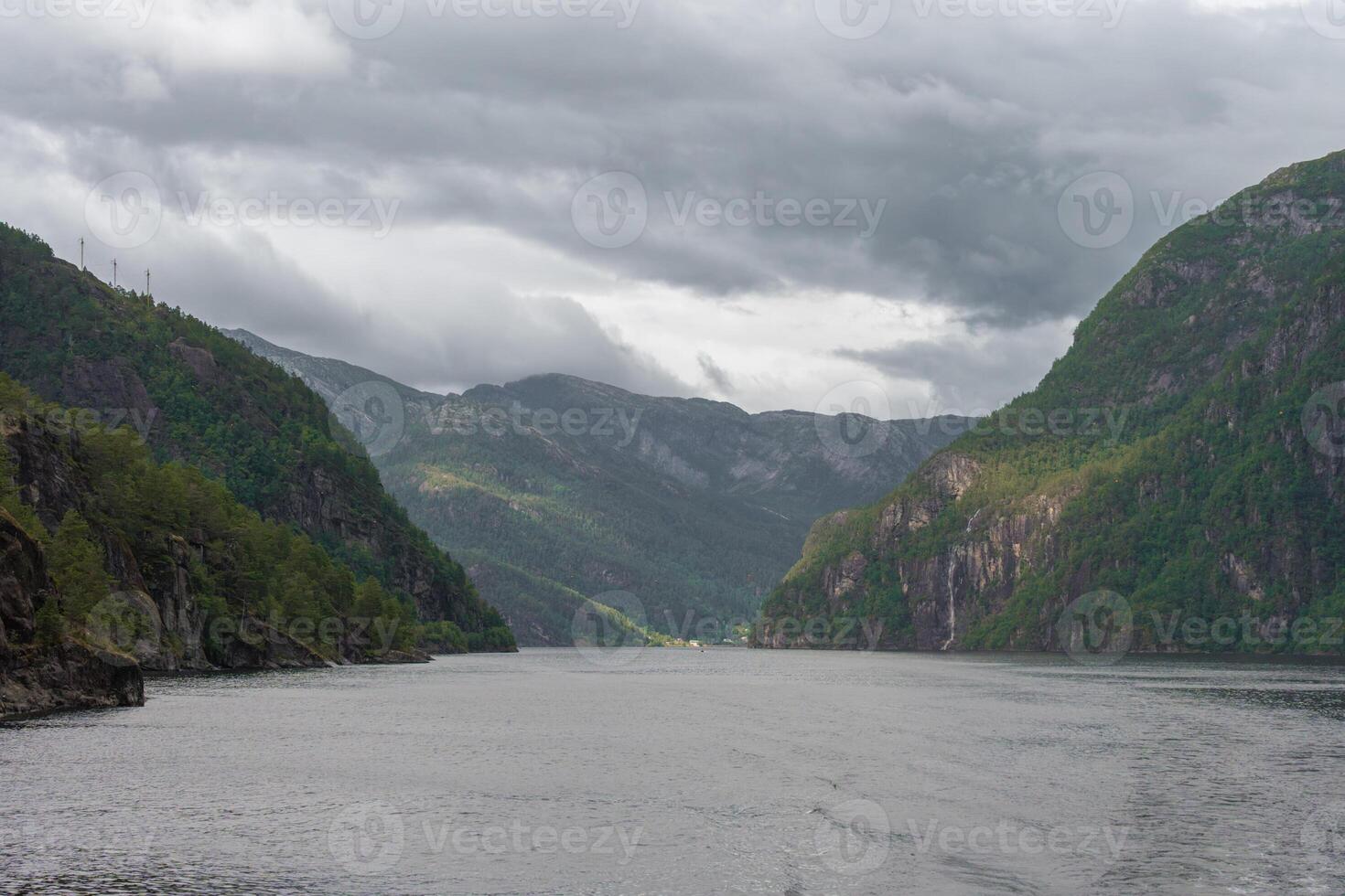 Dramatic fjord landscape with cloudy sky and distant village in Norway photo