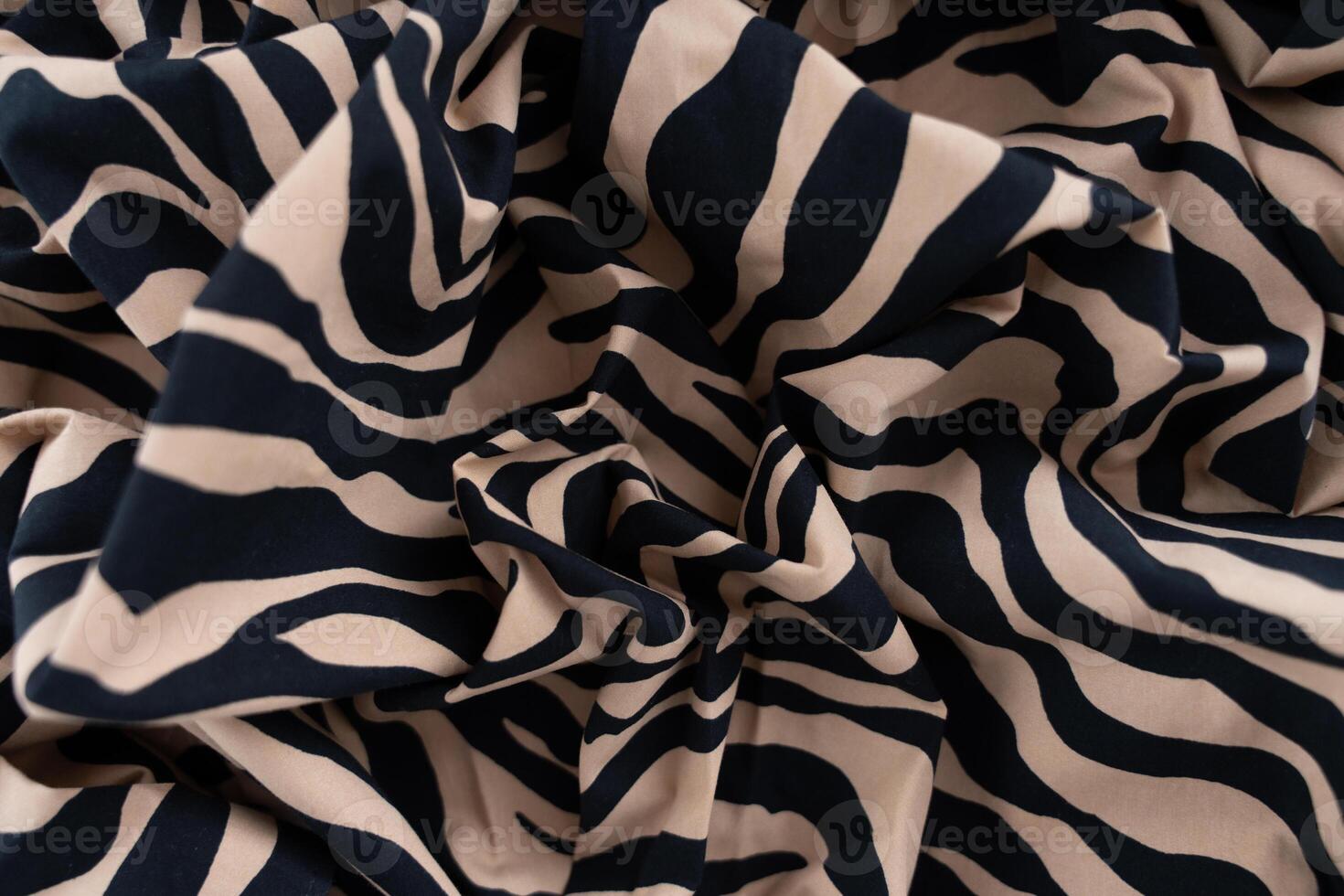 Close-up of beige and black zebra print fabric with soft folds and abstract pattern, selective focus photo