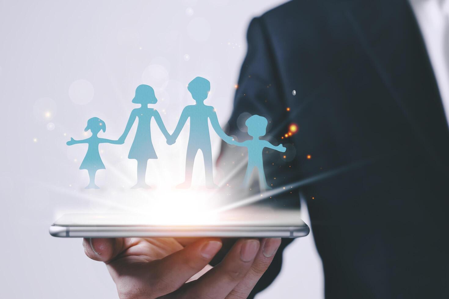 Business man with a smart phone with a blue paper family displayed on a digital virtual screen in the new normal society. Concepts of life insurance, family protection and home stay, save lives photo