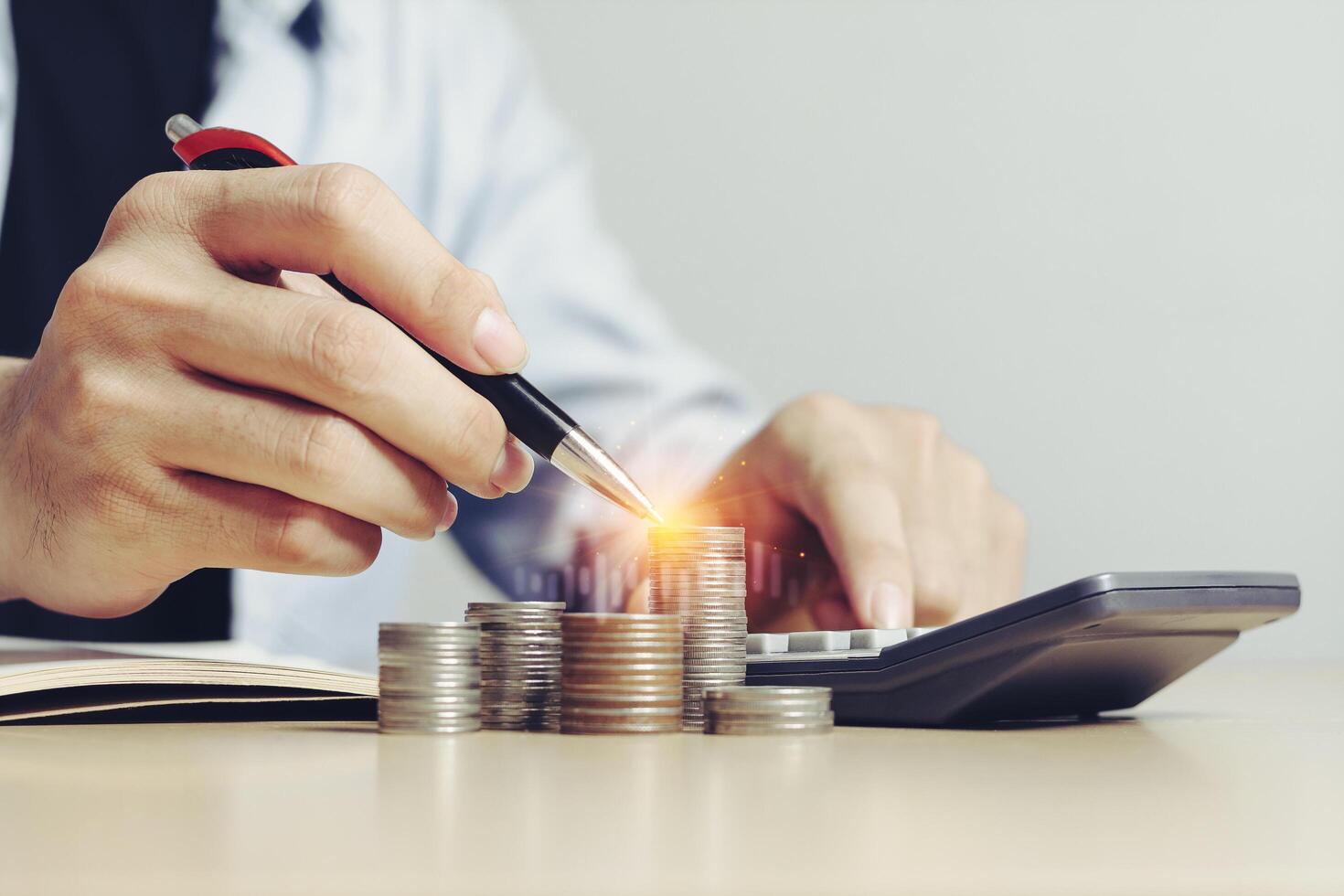 Businessman working using calculator with Money, coins and some stationery on wood table stack in office at home, Front view with copy space. Accounting and financial economic calculation concepts. photo