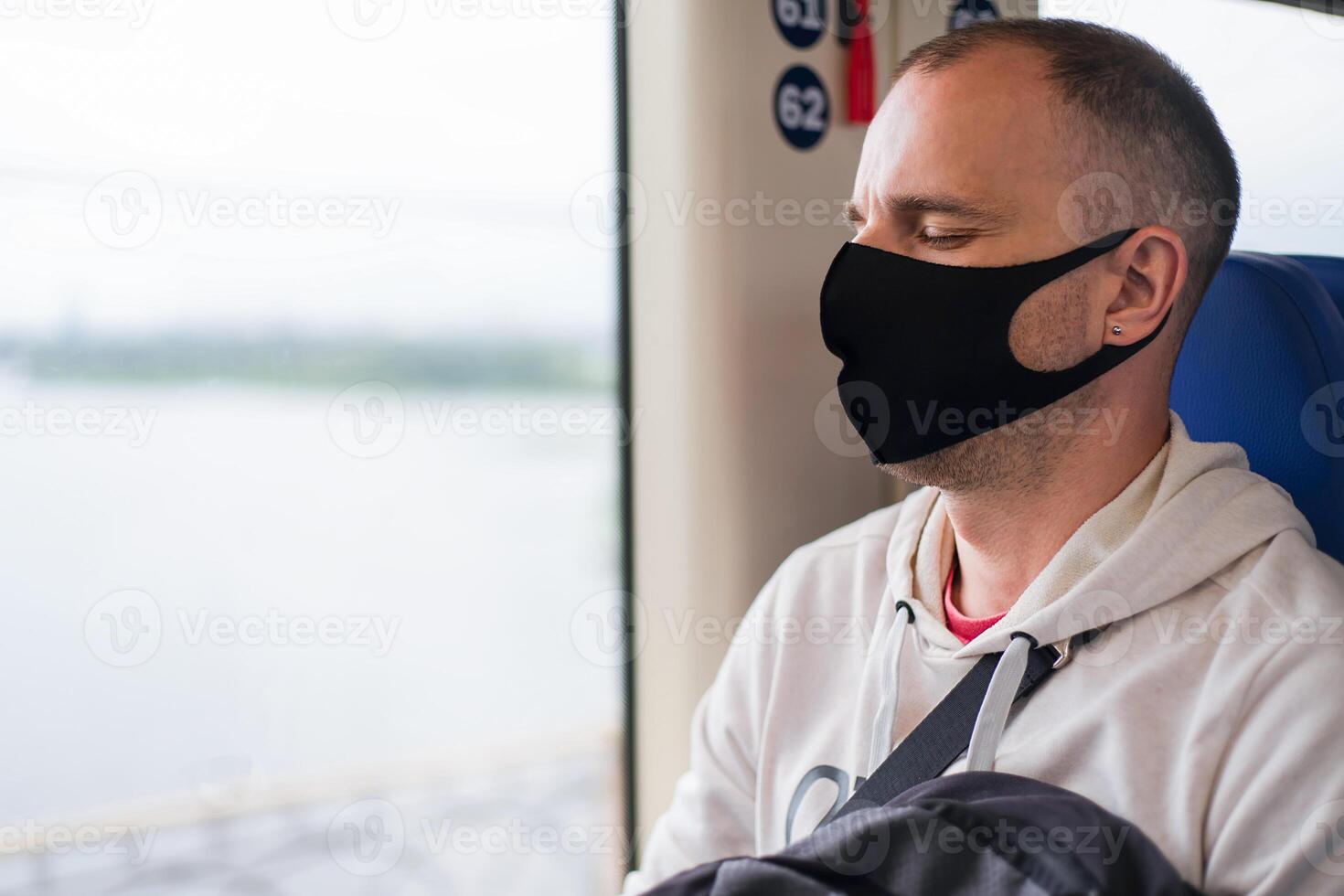 Traveler young man in a protective mask sleeps on the train by the window. Close-up. Copy space. photo