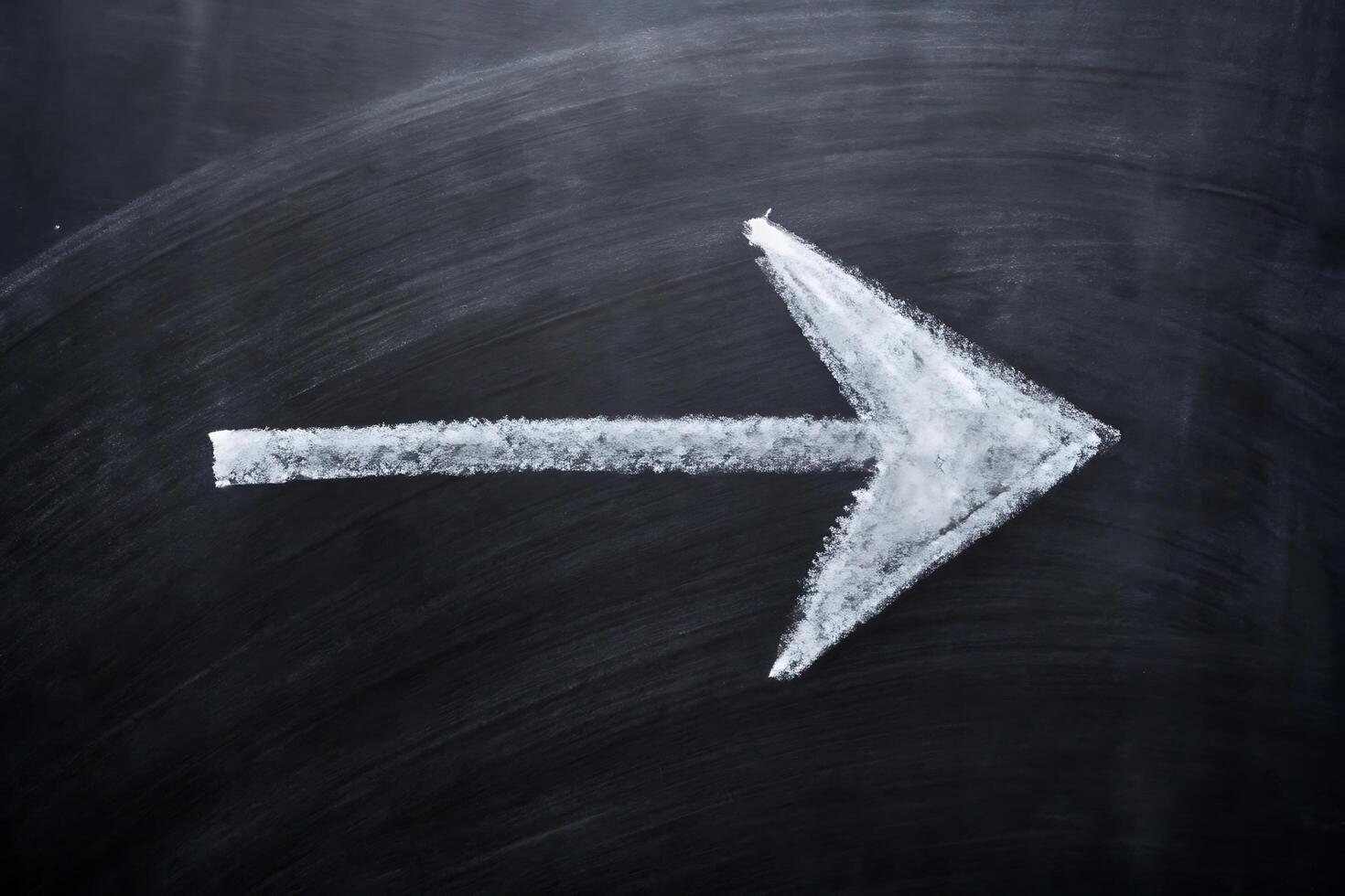 Hand-Drawn White Arrow Pointing Right on Blackboard Suggesting Direction photo