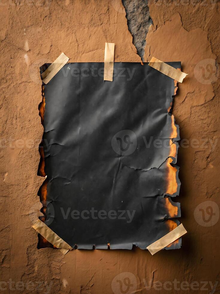 Dark burnt paper sheet on cracked wall with adhesive tape abstract background photo