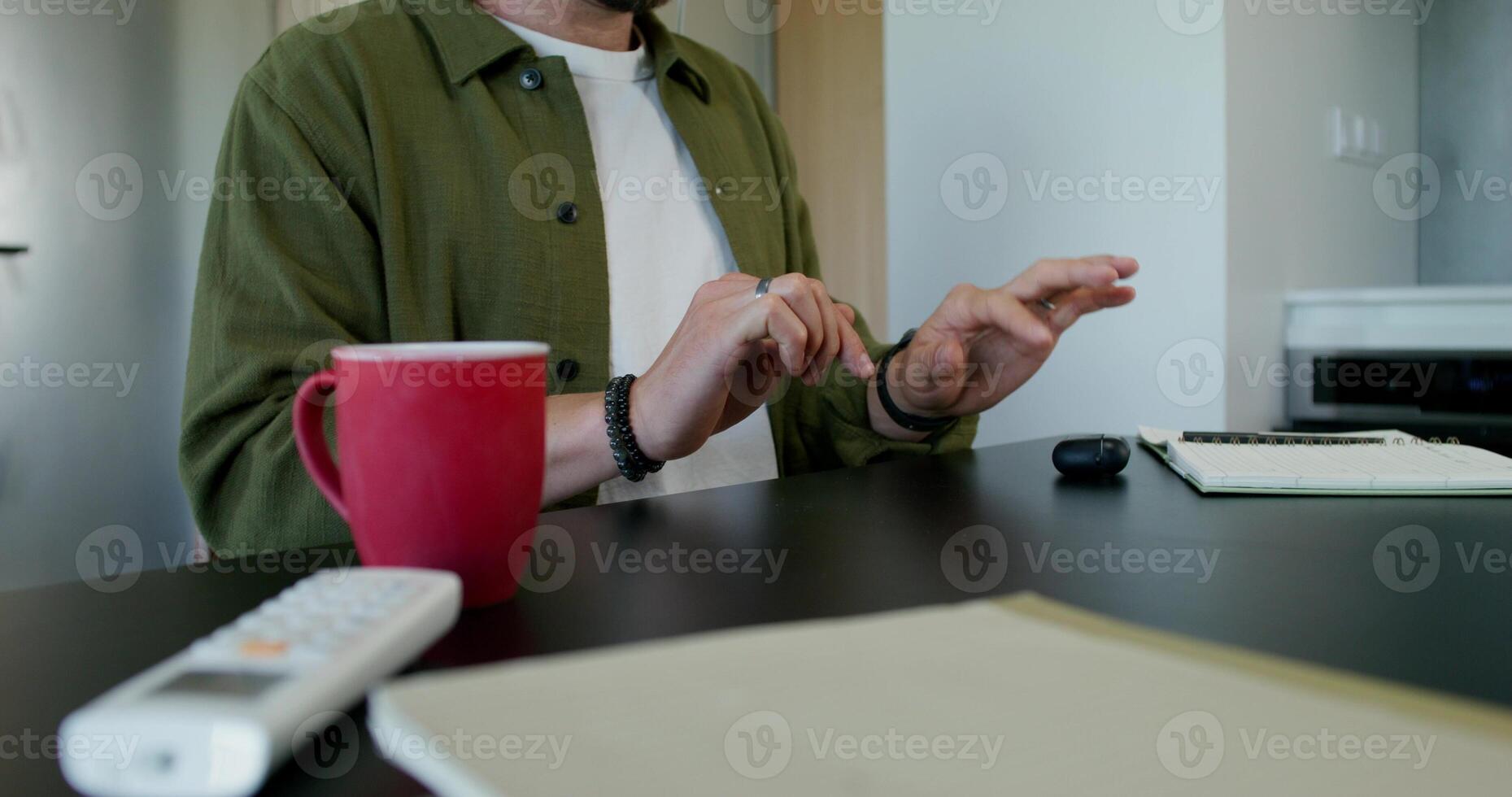 A man in a virtual reality headset typing on a virtual keyboard sitting at a table at home. Daylight - virtual photo