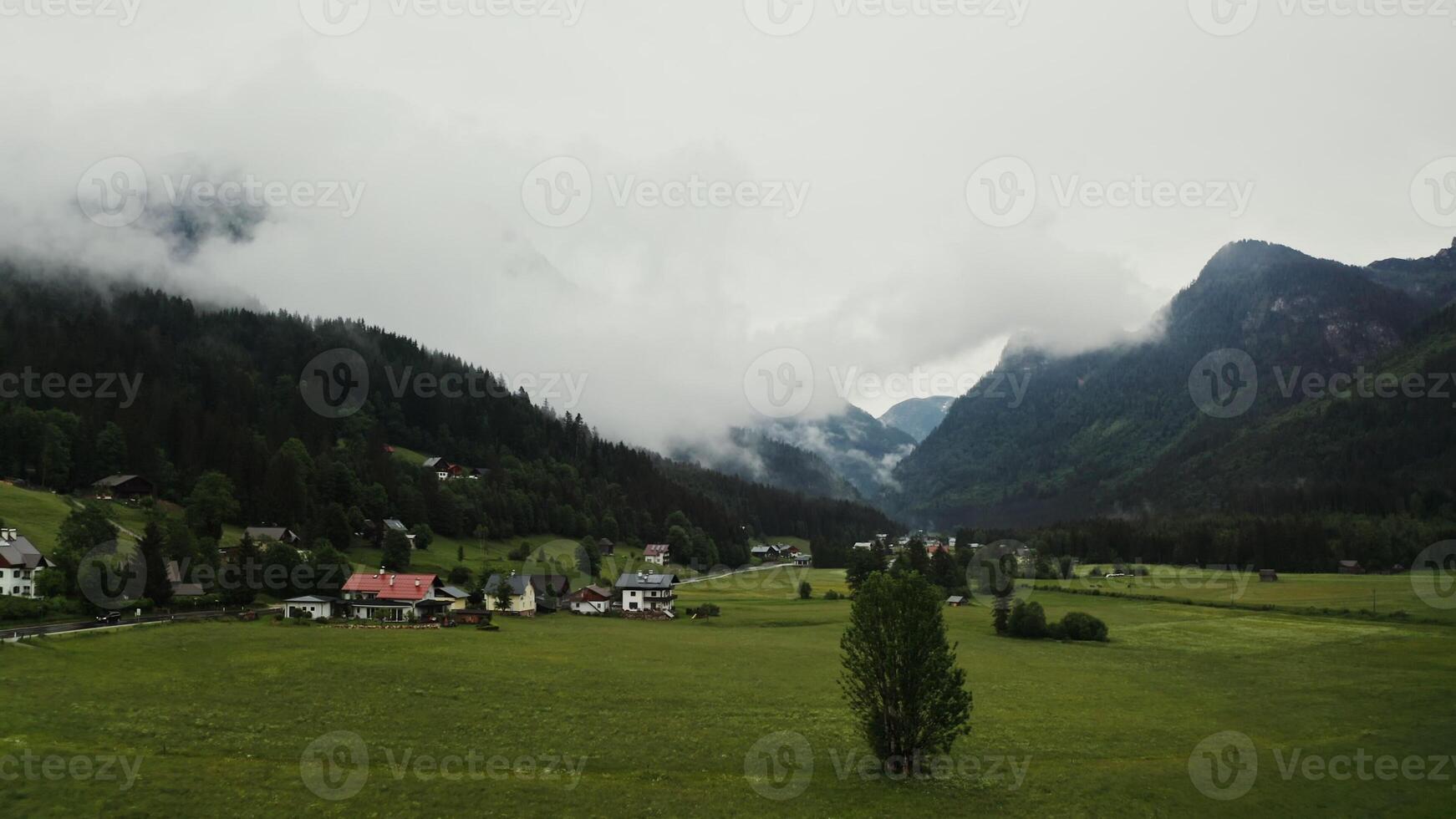 The picturesque nature of Austria from a bird's eye view. View of the village, located in a lowland between high mountains, covered with white clouds. - Austria photo