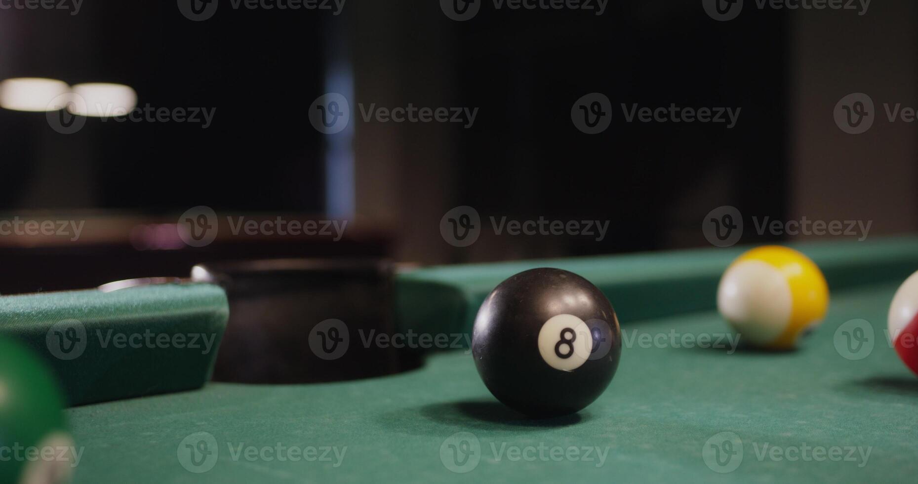 A billiard ball flies into the hole, close-up. No people in the , just a pool table, vertical photo