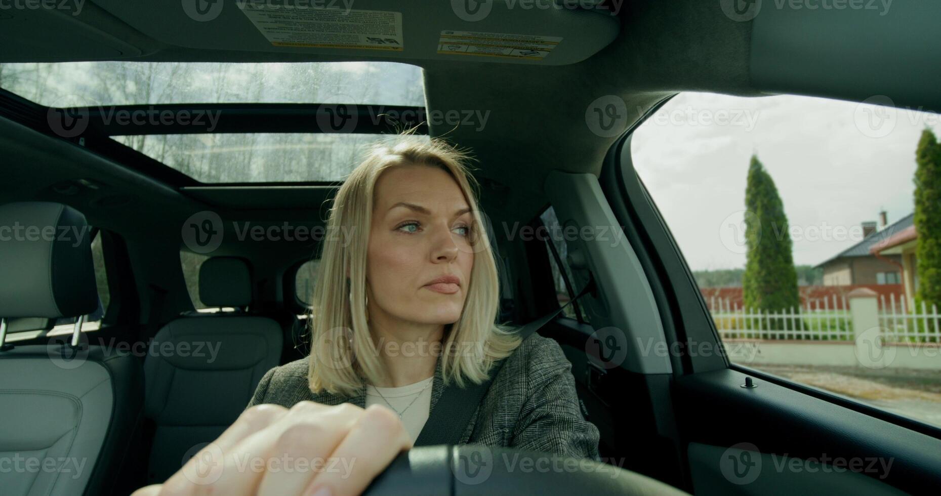 A business woman drives a car around the city on a sunny day. Front view - around photo
