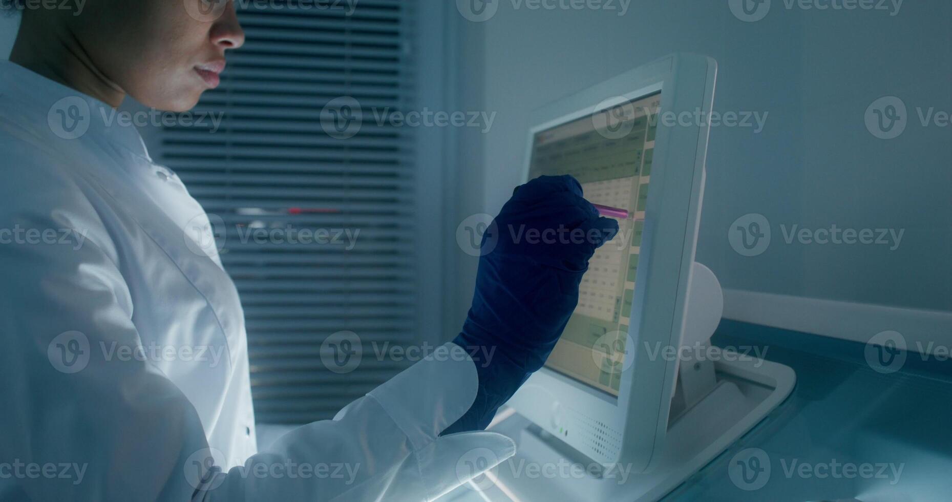 Work in a medical laboratory. A woman in a lab coat, disposable gloves and safety glasses sets up a blood splitting device using a screen - medical photo