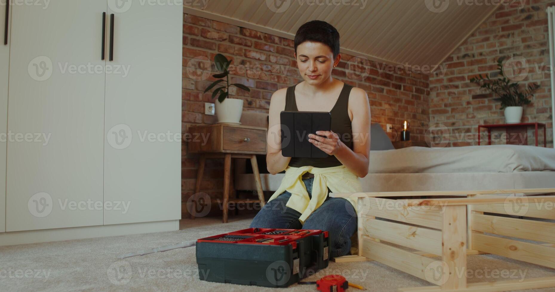 A woman selects tools from a toolbox by assembling a rack while sitting on the floor at home - assembling photo