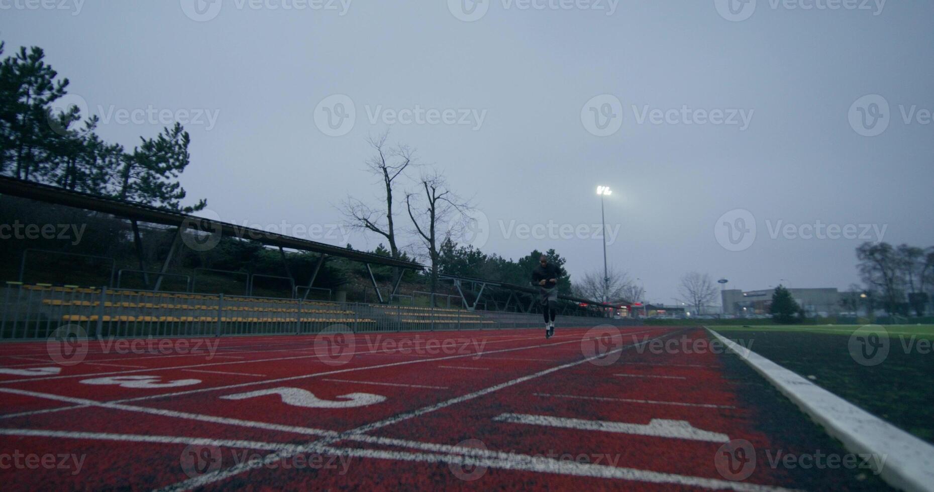 A man in sports clothes runs around the stadium on a cold day alone photo