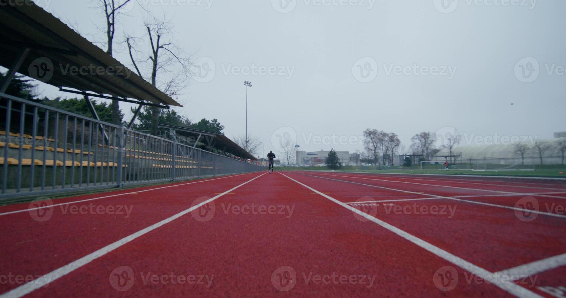 A man in sports clothes runs around the stadium on a cold day alone, front view - sports photo
