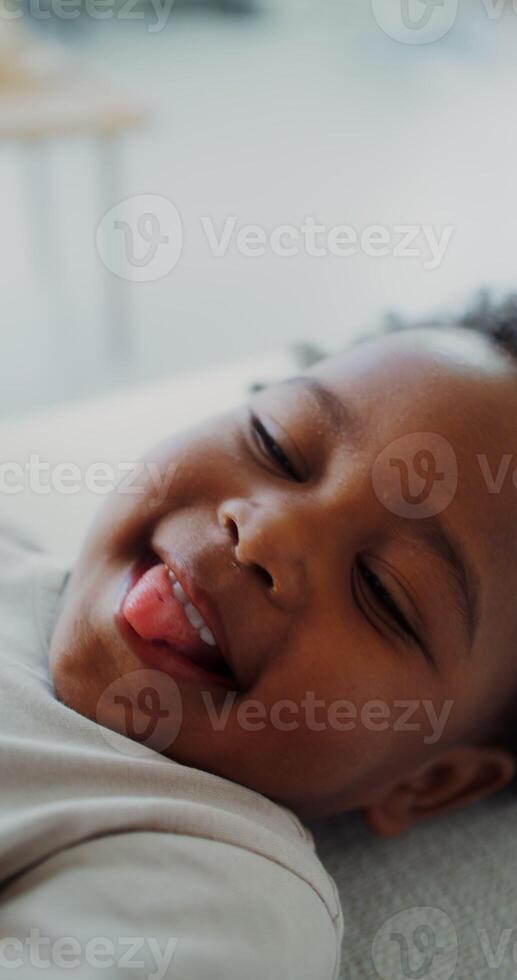 Close-up of a smiling face of an African-American child while playing with his mother lying on the couch at home - mother photo