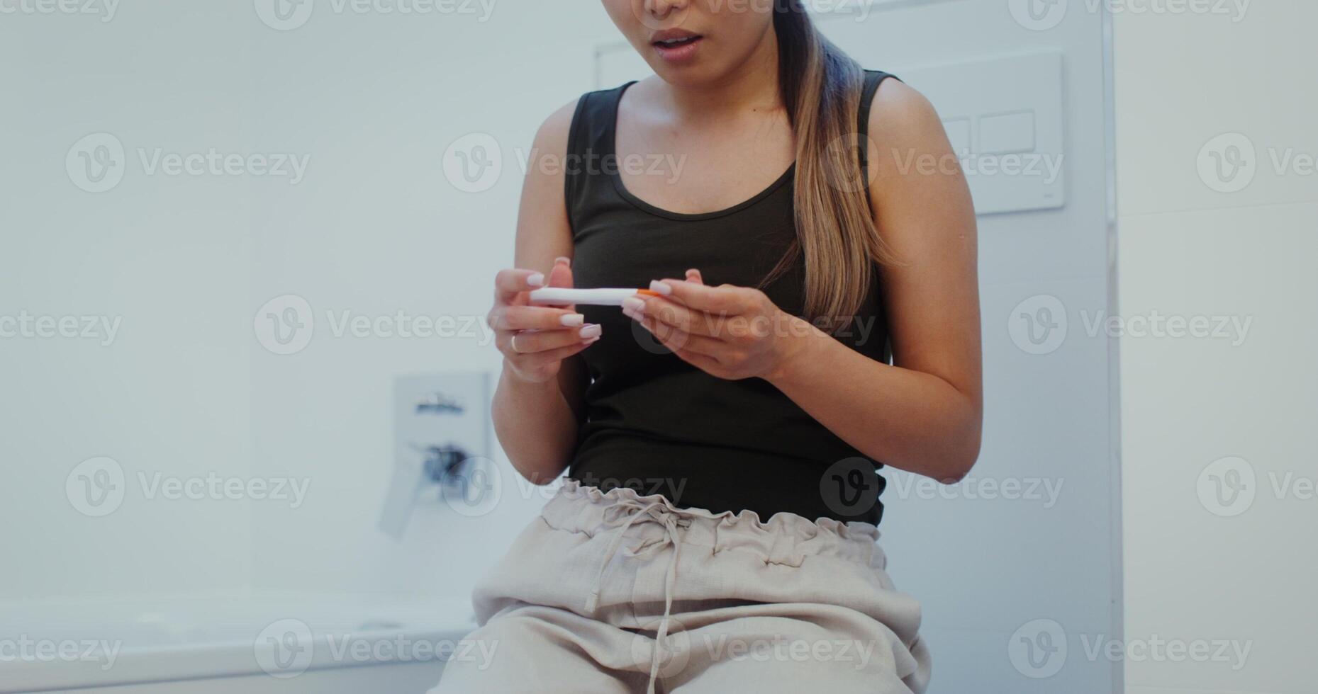 A young woman is worried about waiting for the result of a pregnancy test and rejoices at the positive result photo