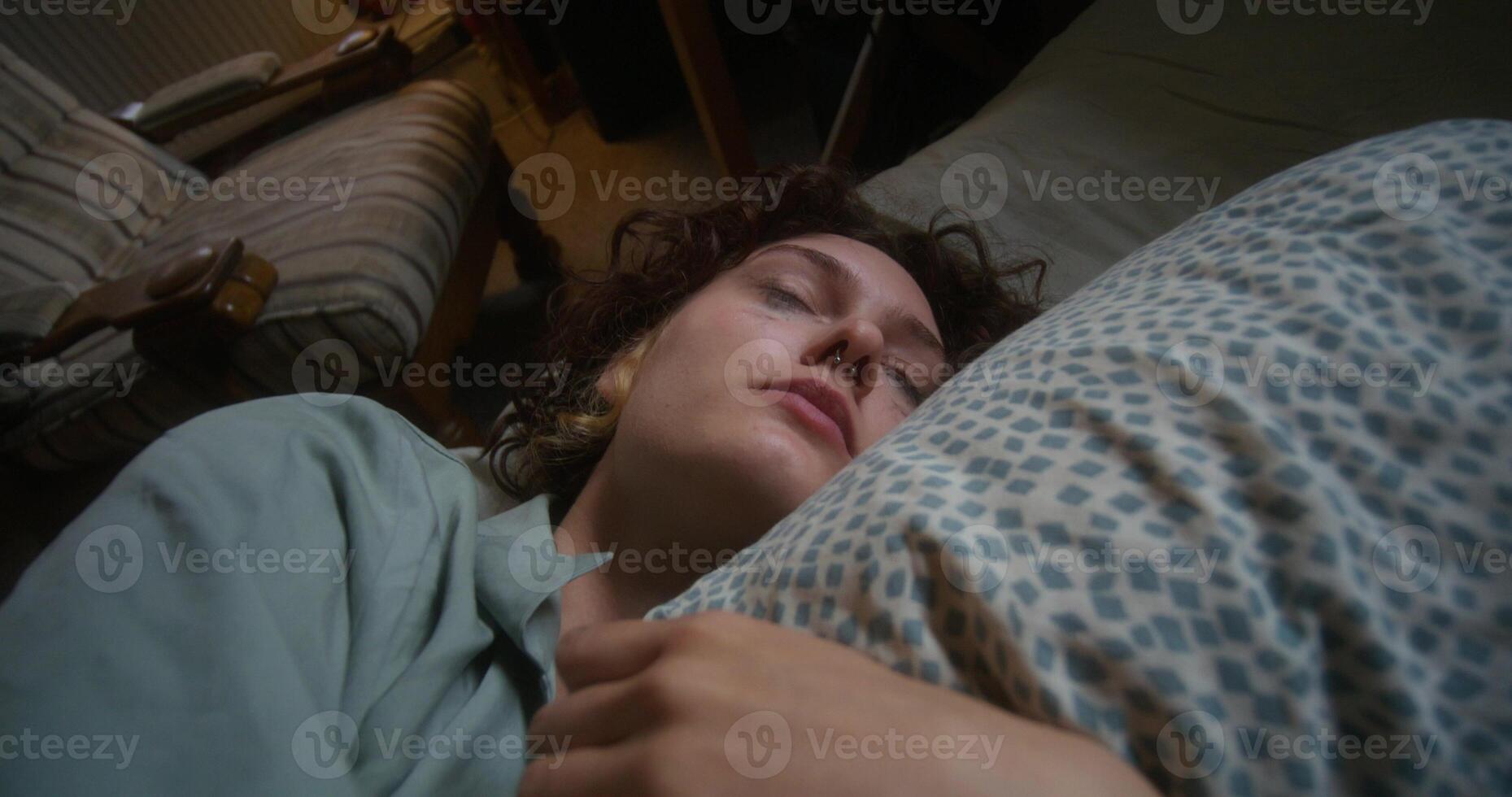 A woman is crying and hugging a pillow lying in bed at home. The mascara is smeared under the eyes - pillow photo