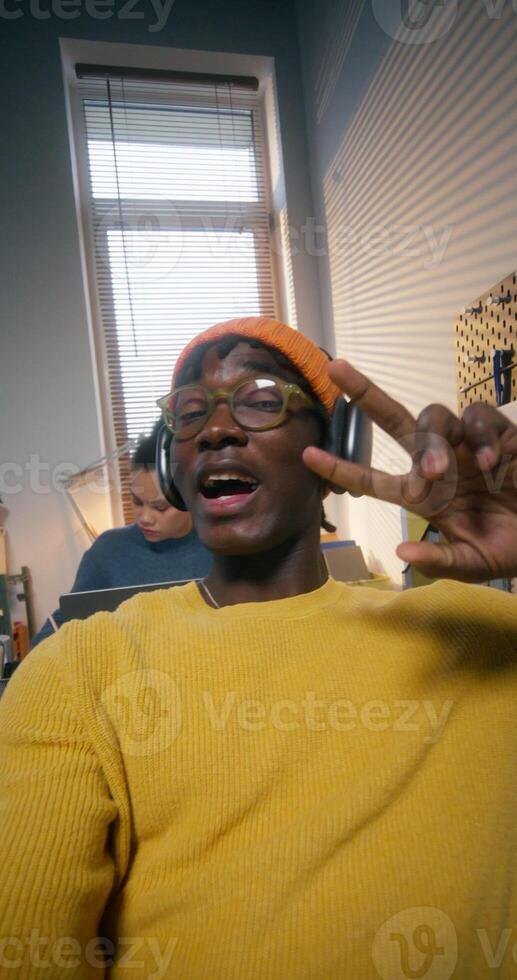 A man in a hat and headphones smiles while chatting on chat and looking at the camera as at a computer screen photo