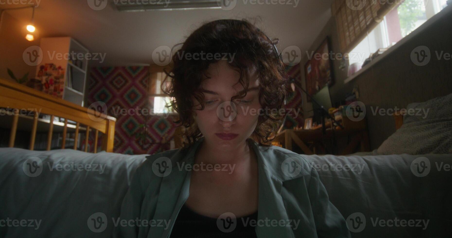 A young woman uses a laptop sitting on the floor in the bedroom at home with a serious look - laptop photo