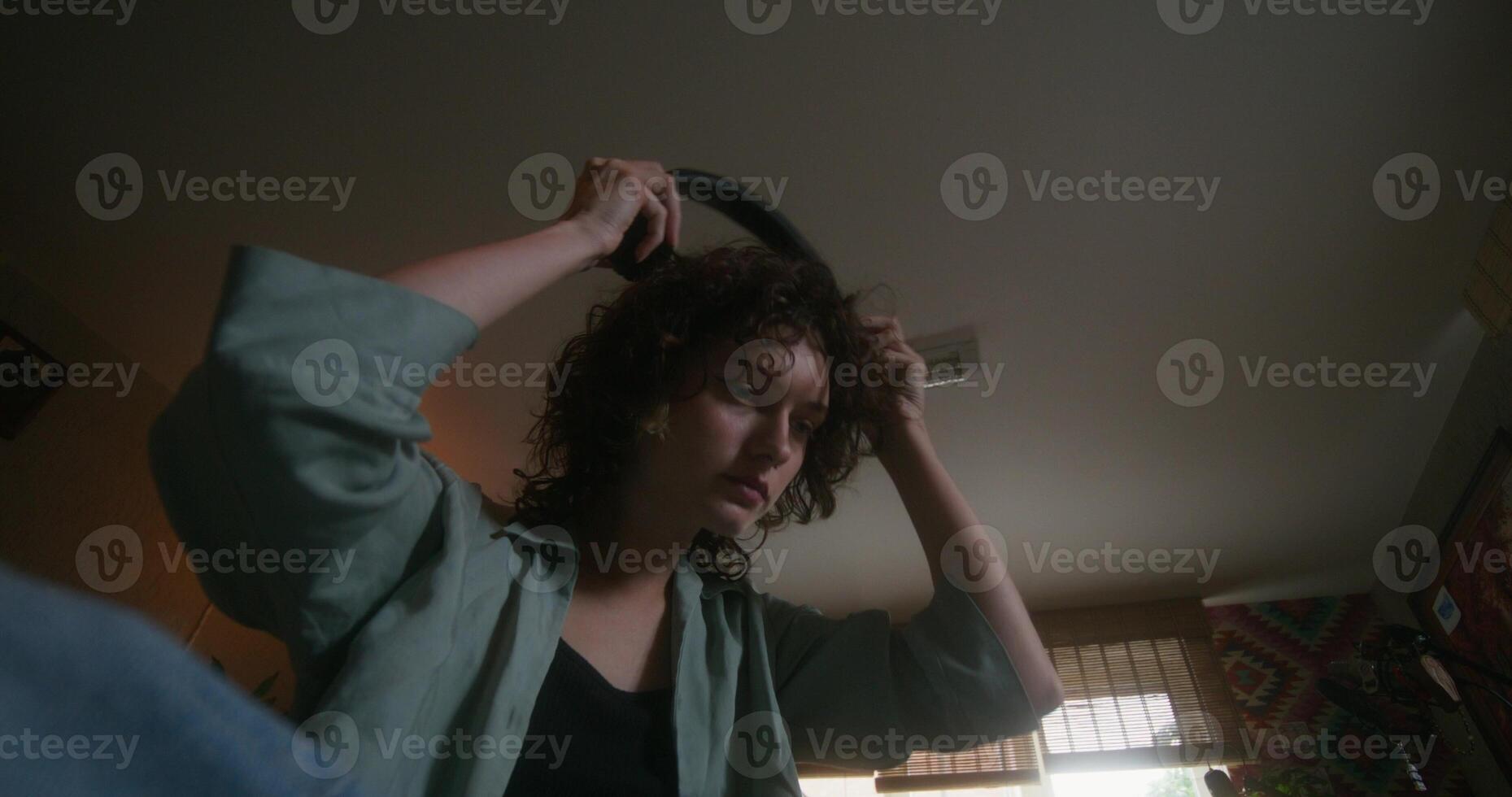 A young woman puts on headphones and uses a mobile phone sitting on the bed. She is upset or depressed. Teenage home interior - Teenage photo