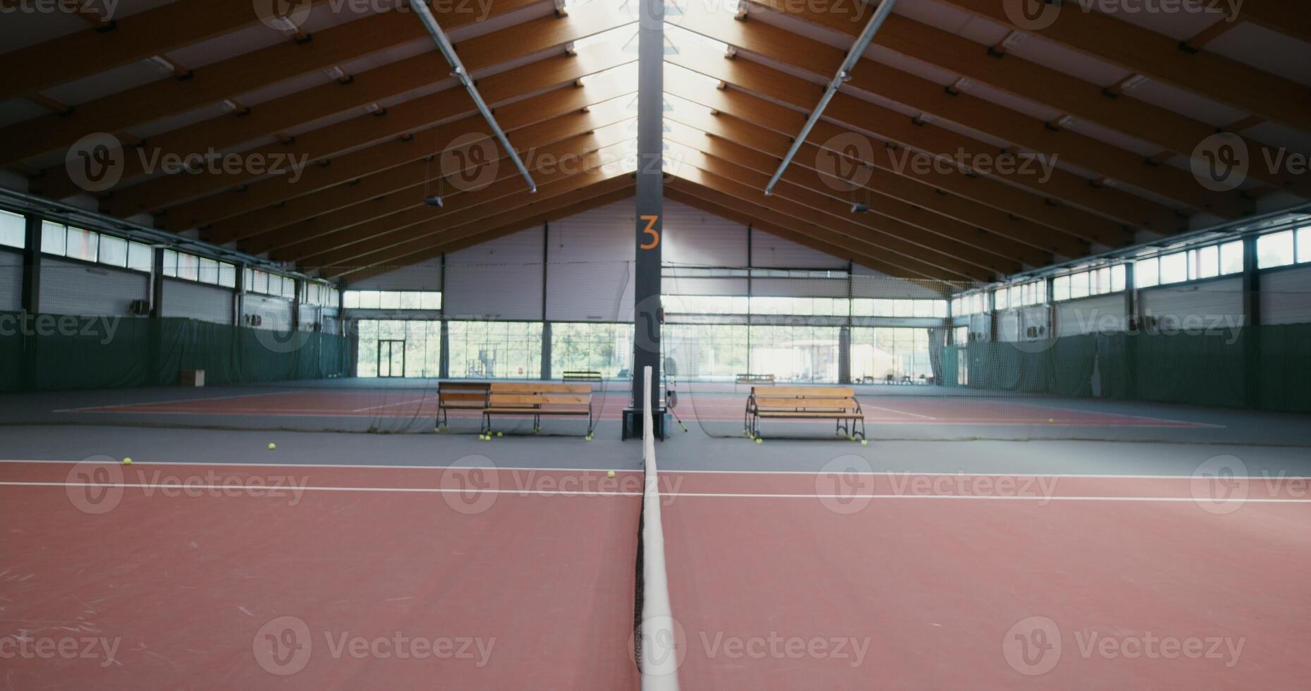 Two men of European appearance greet each other, shaking hands across the net stretched across the tennis court, about to play tennis in the indoor tennis court - shaking photo