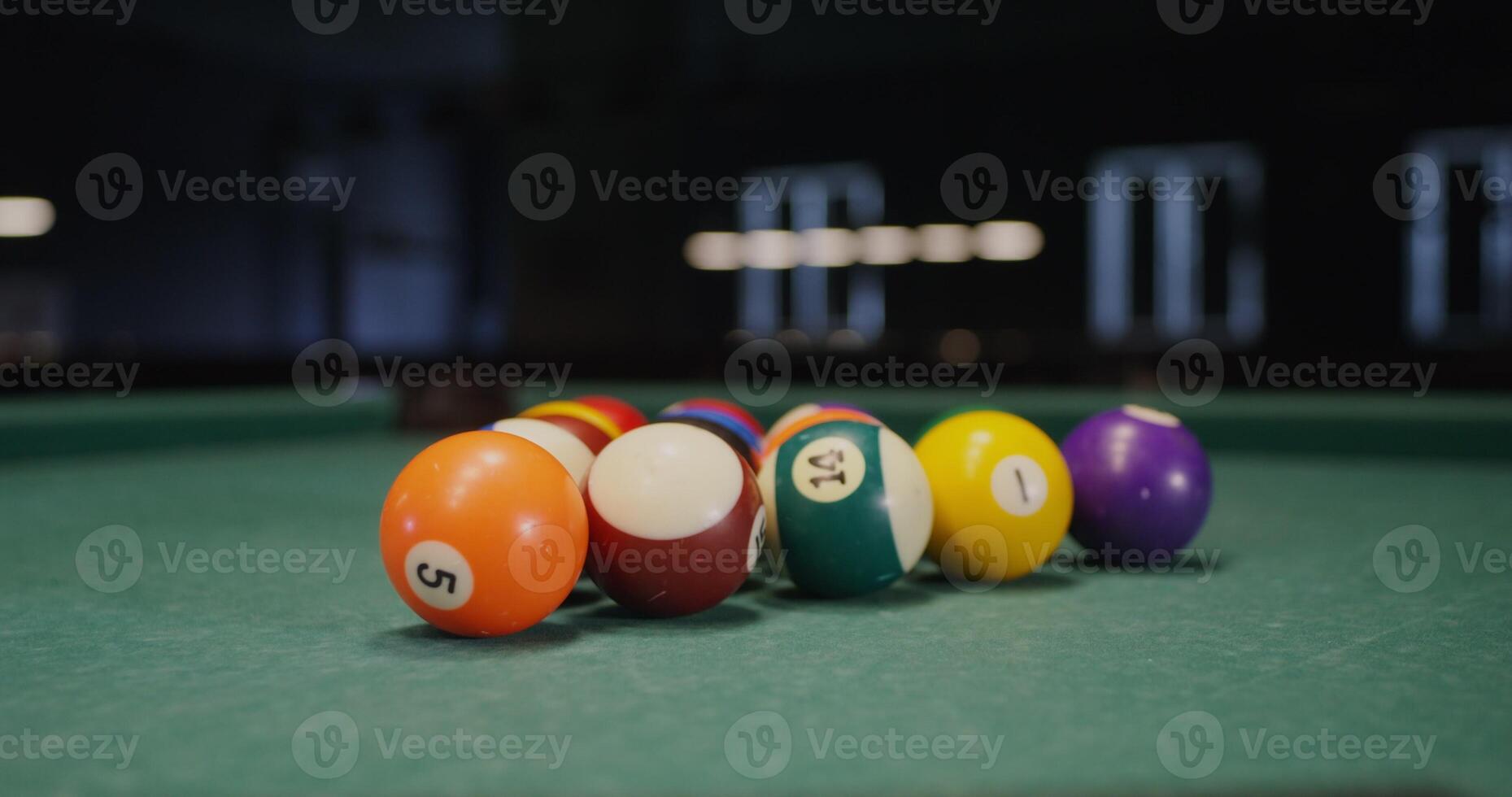 White billiard ball breaks a triangle of colored balls that fly to the sides, one ball flies into the hole, close-up, no people in the - colored photo