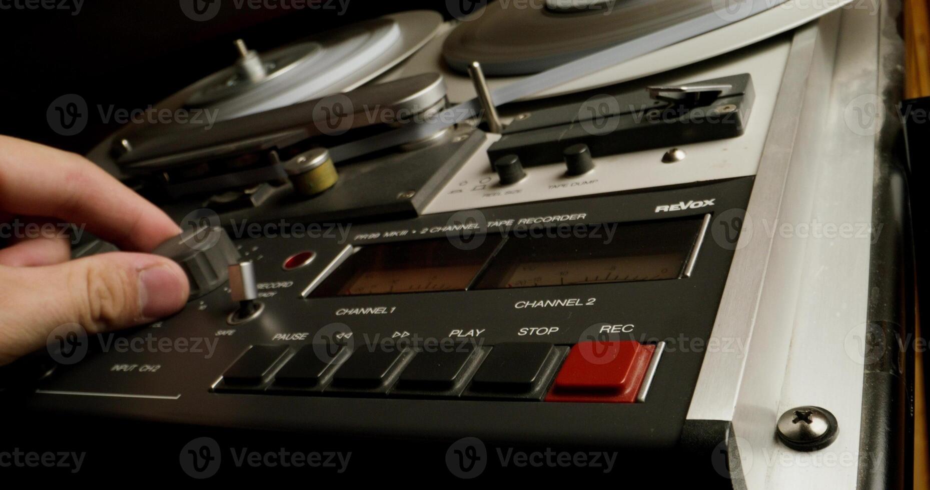 A man controls a professional tape recorder for recording on magnetic tape. Close-up of his hands, an unrecognizable person. Recording Studio photo