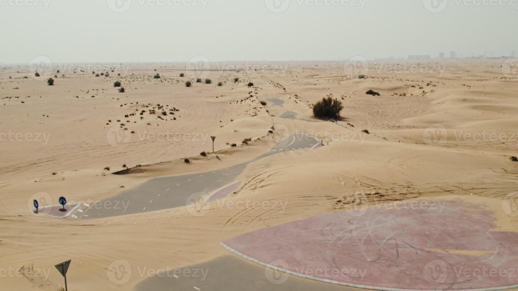 The drone flies over a modern paved road with a roundabout covered with desert sands photo